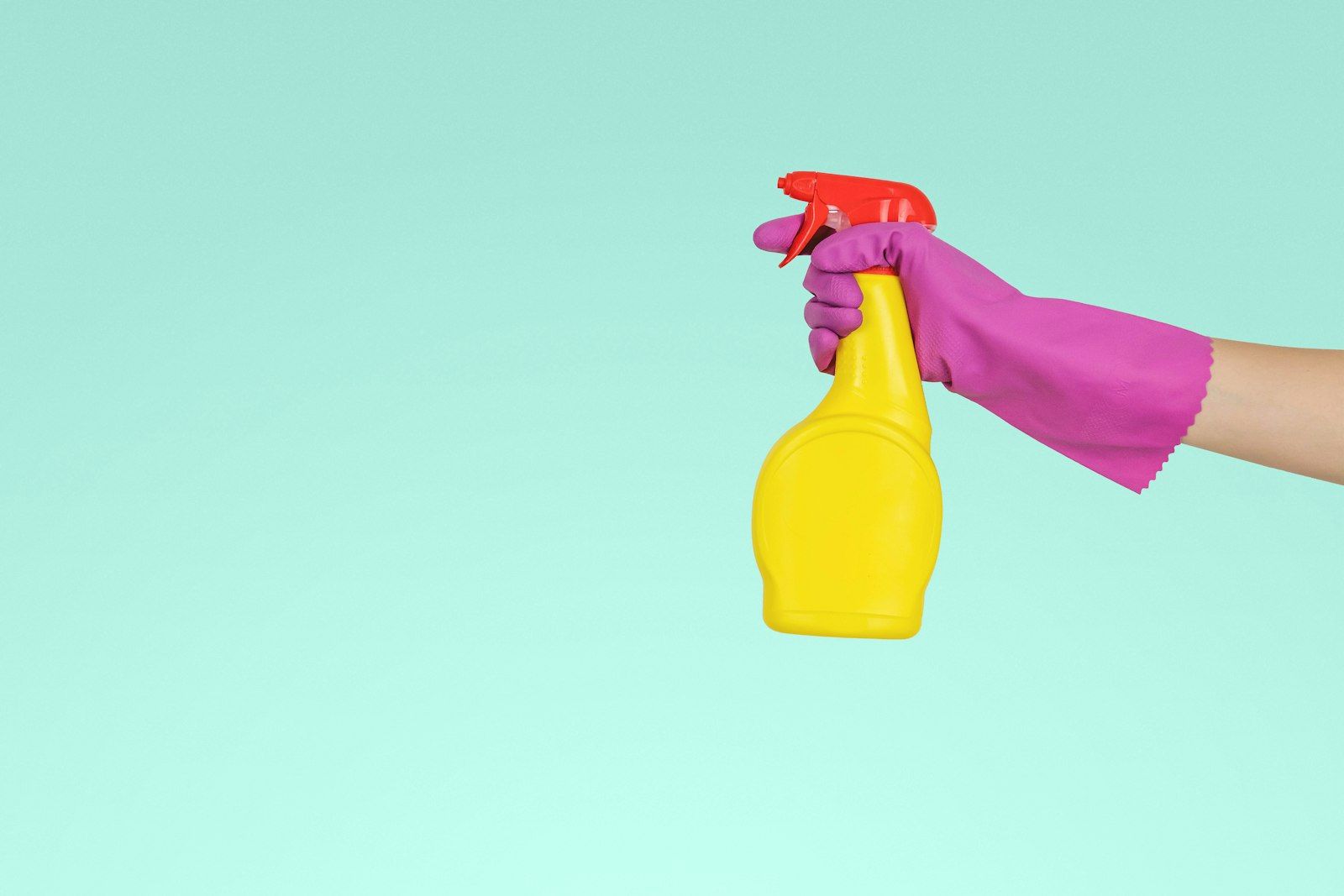 Cleaning spray bottle held against a teal background