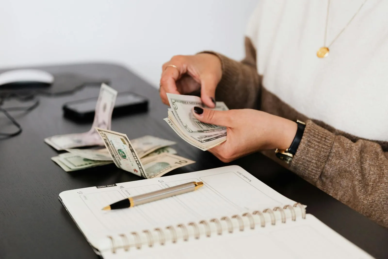 Comparing cleaning service quotes with notebook and cash