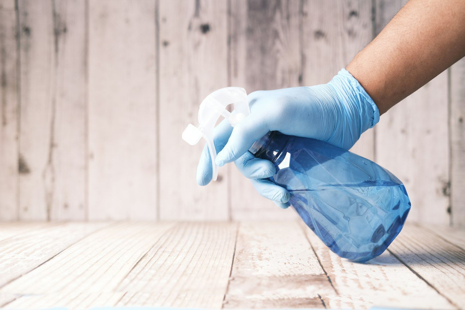 Eco-friendly blue spray bottle on a wooden surface