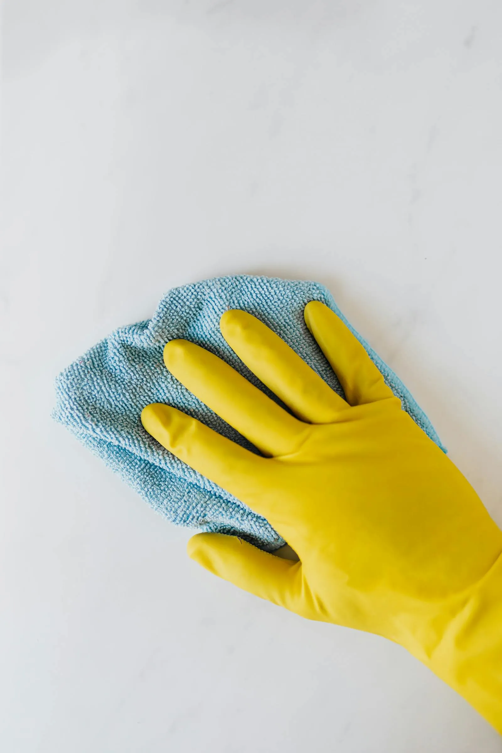Wiping a marble surface with gloved hands and microfiber
