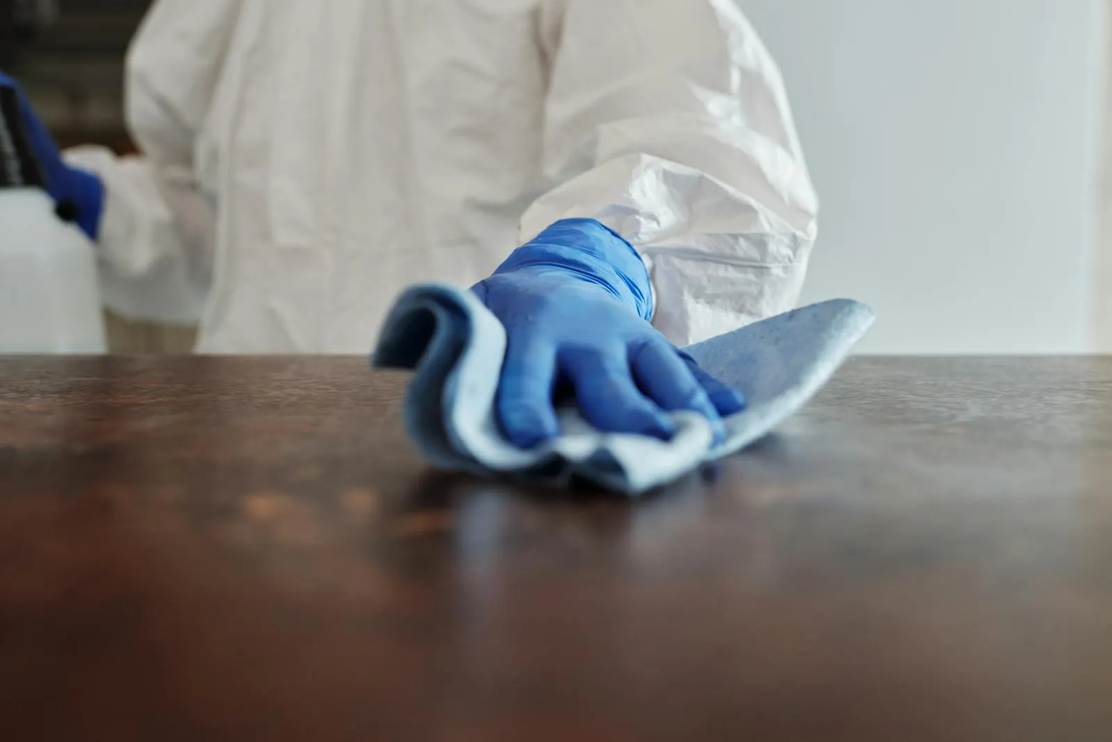 Technician disinfecting an office surface with a microfiber cloth
